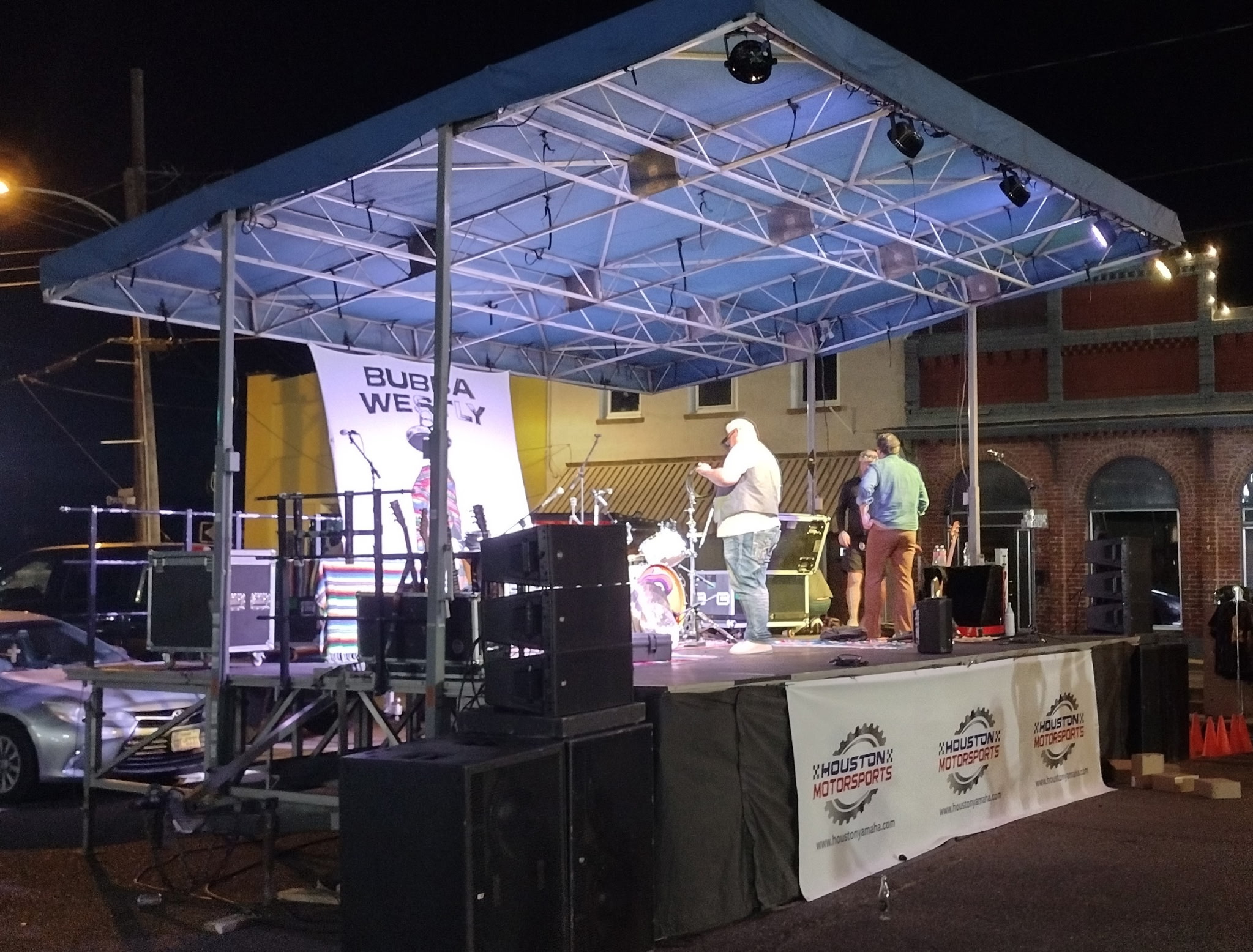 View from front-of-house toward lit stage with audience hands raised